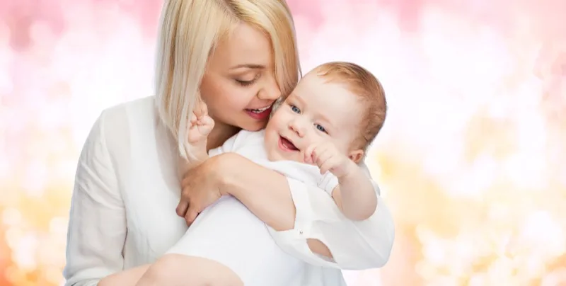 A mother cheek to cheek with her laughing baby