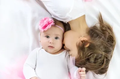 A baby in a flower headband being kissed by her mother